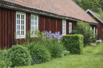 Gammel rødmalt arbeiderbolig i hagemiljø